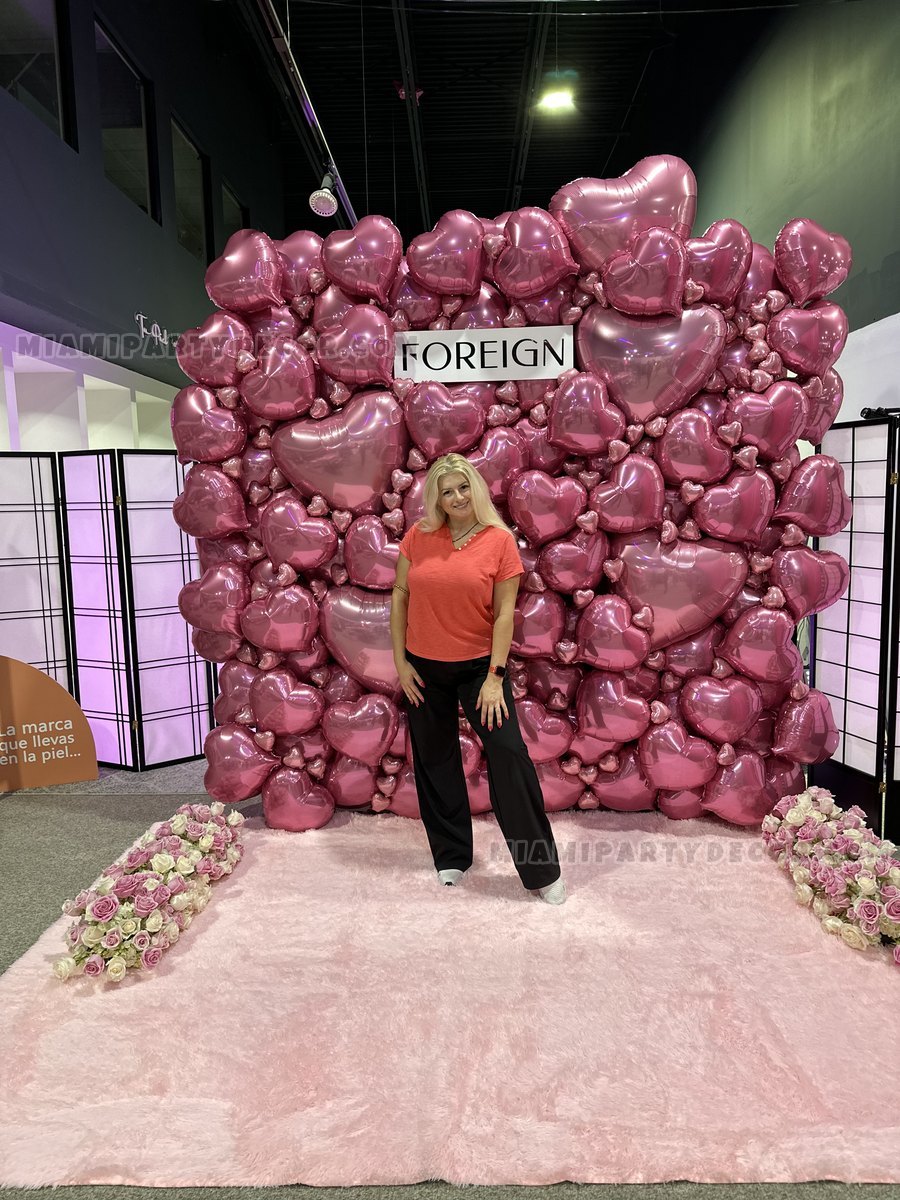 Olesia Standing In Front Of A Pink Heart-Shaped Balloon Wall